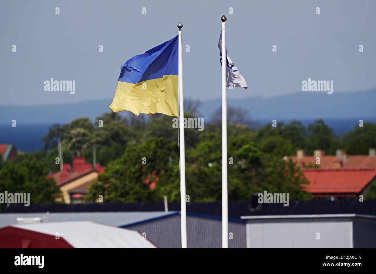 Saisonales Wetter, die ukrainische Flagge vor einem Unternehmen am Dienstag in Vadstena, Schweden. Stockfoto