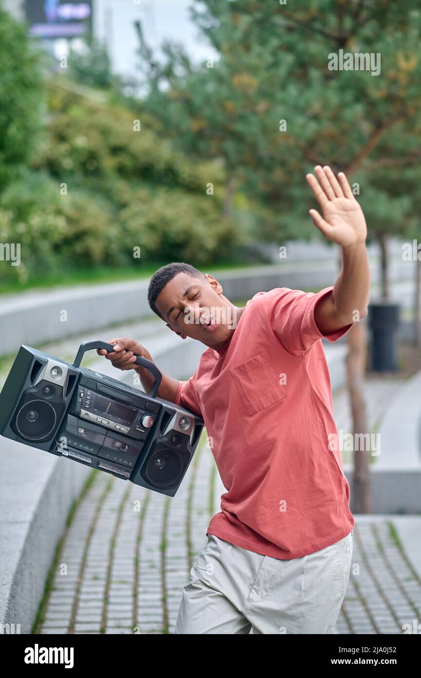 Typ mit Plattenspieler in Tanzbewegung im Park Stockfoto