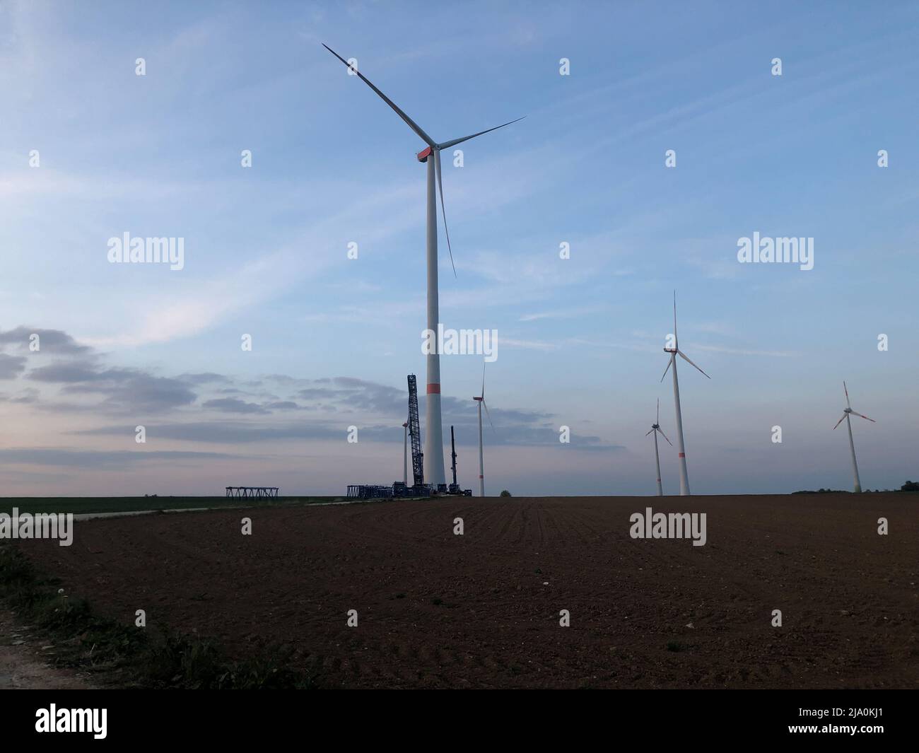 Bau von Windkraftanlagen zur Stromerzeugung im Sonnenuntergang. Stockfoto