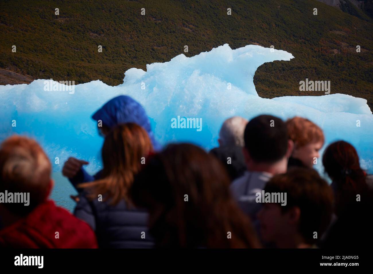 Touristen stehen vor einem blauen Eisberg während der Fahrt im Argentino See, Los Glaciares Nationalpark, Argentinien. Stockfoto