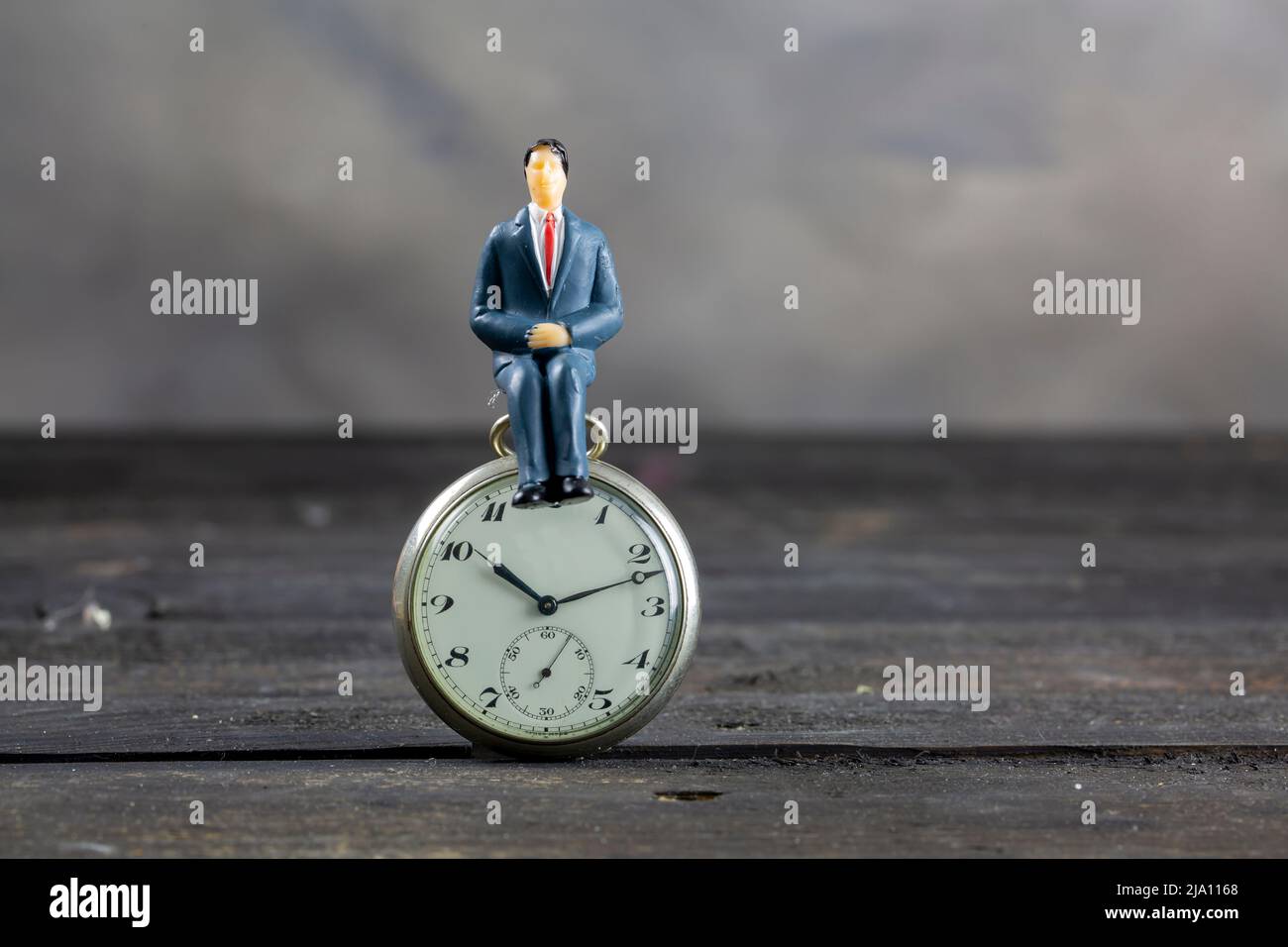 Geschäftsmann sitzt auf einer Uhr. Zeitkonzept. Stockfoto