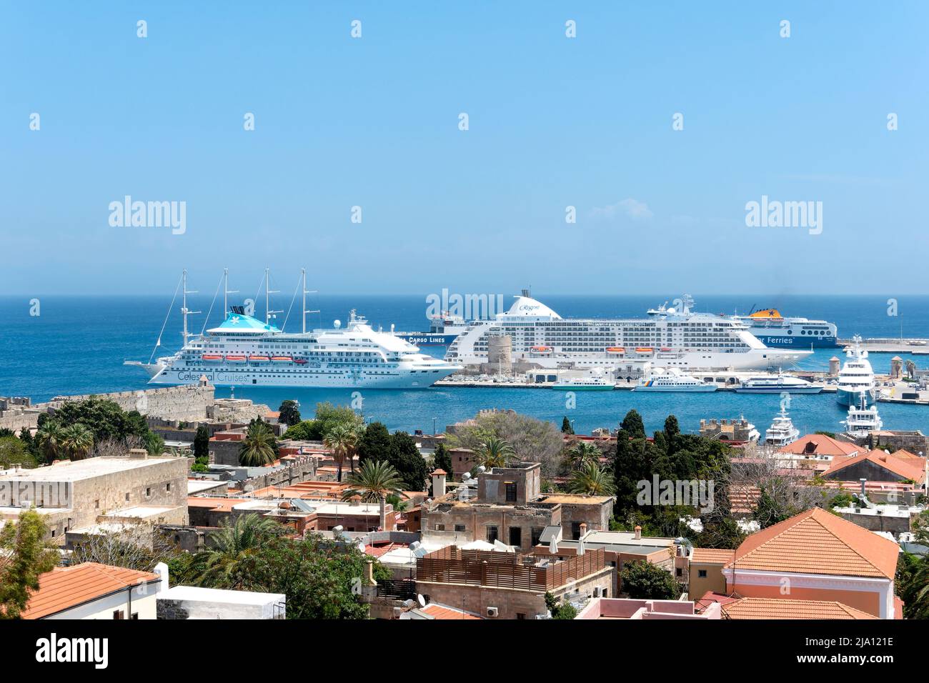 Ein Blick über Rhodos-Stadt, Rhodos in Richtung des alten Hafens und der Mandraki Marina zeigt zwei große Kreuzfahrtschiffe, die während des Besuchs der berühmten Stadt vor Anker liegen Stockfoto