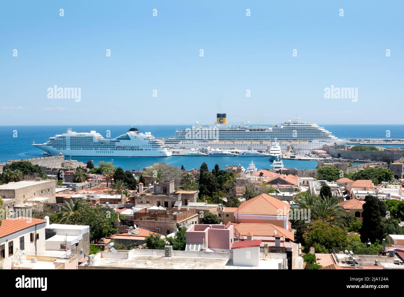 Ein Blick über Rhodos-Stadt, Rhodos in Richtung des alten Hafens und der Mandraki Marina zeigt zwei große Kreuzfahrtschiffe, die während des Besuchs der berühmten Stadt vor Anker liegen Stockfoto