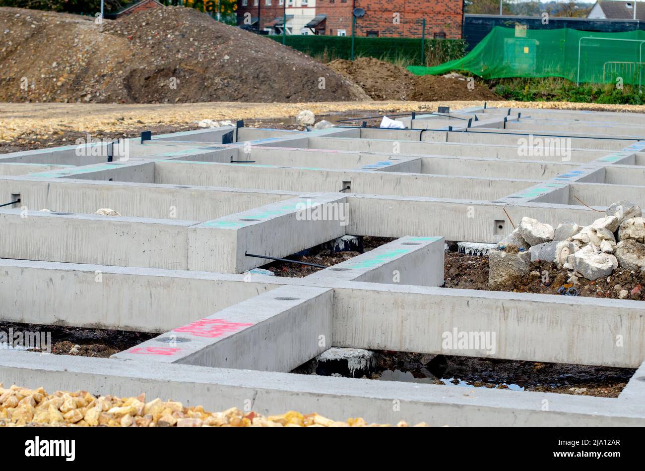 Vorgegossene Betonbalken, die auf den Pfählen als Grundlage für ein neues mehrstöckiges Wohngebäude platziert werden Stockfoto