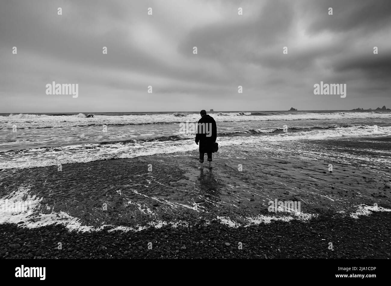 Einsame Figur an einem stürmischen Strand Stockfoto