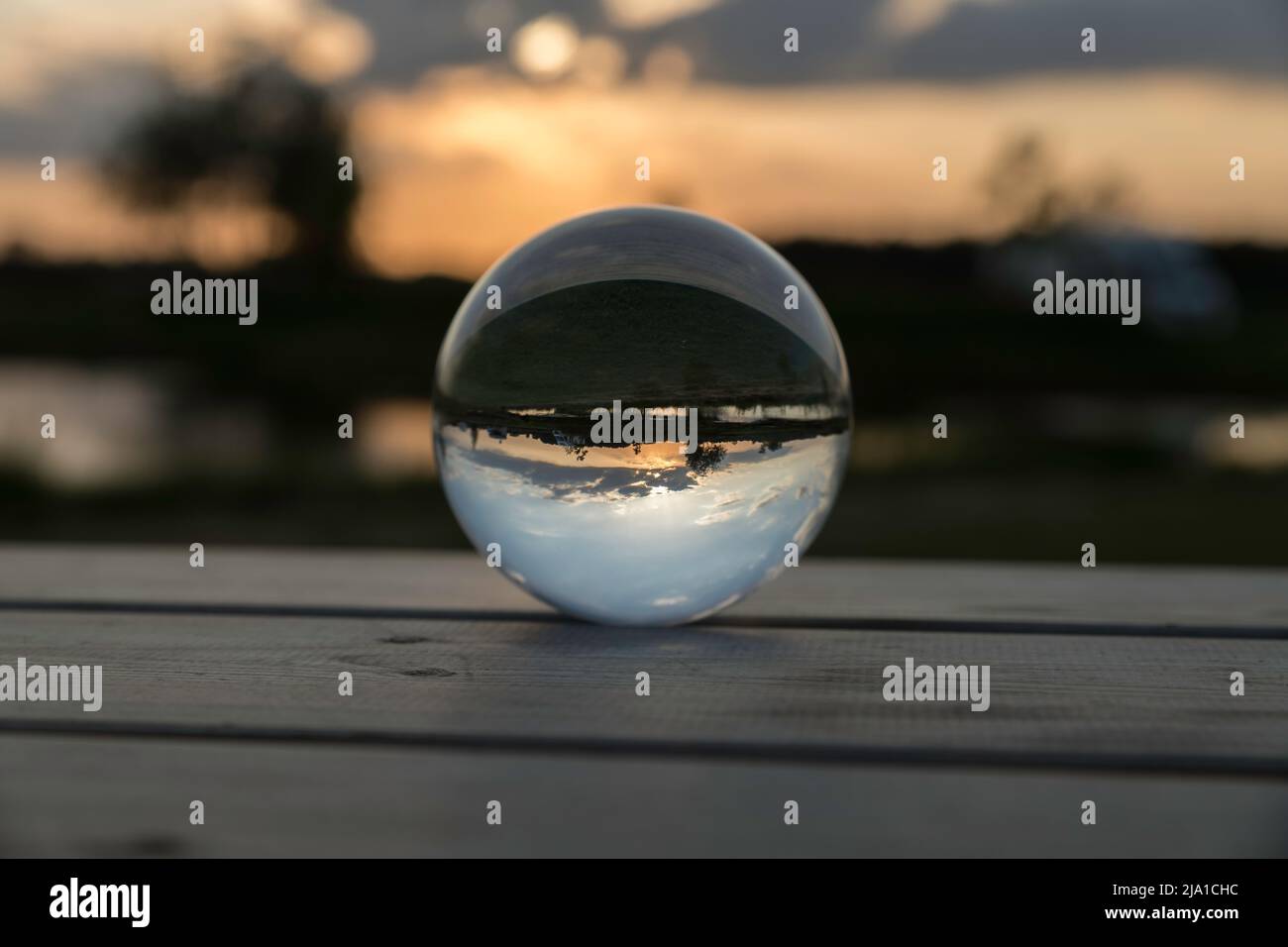 Sonnenuntergang in einer Glaskugel auf einem Holztisch Stockfoto