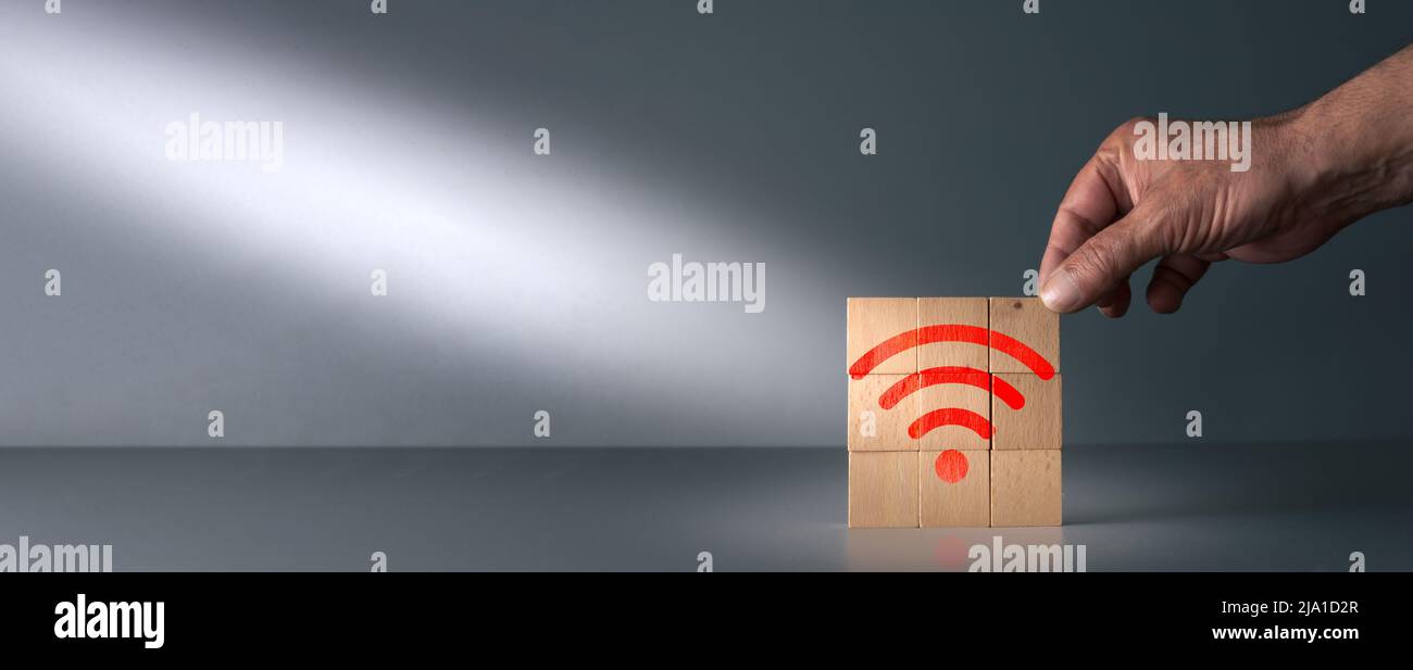 Handposierte Holzklotz mit wi-Fi-Symbol in rot auf grauem Hintergrund mit Kopierraum Stockfoto