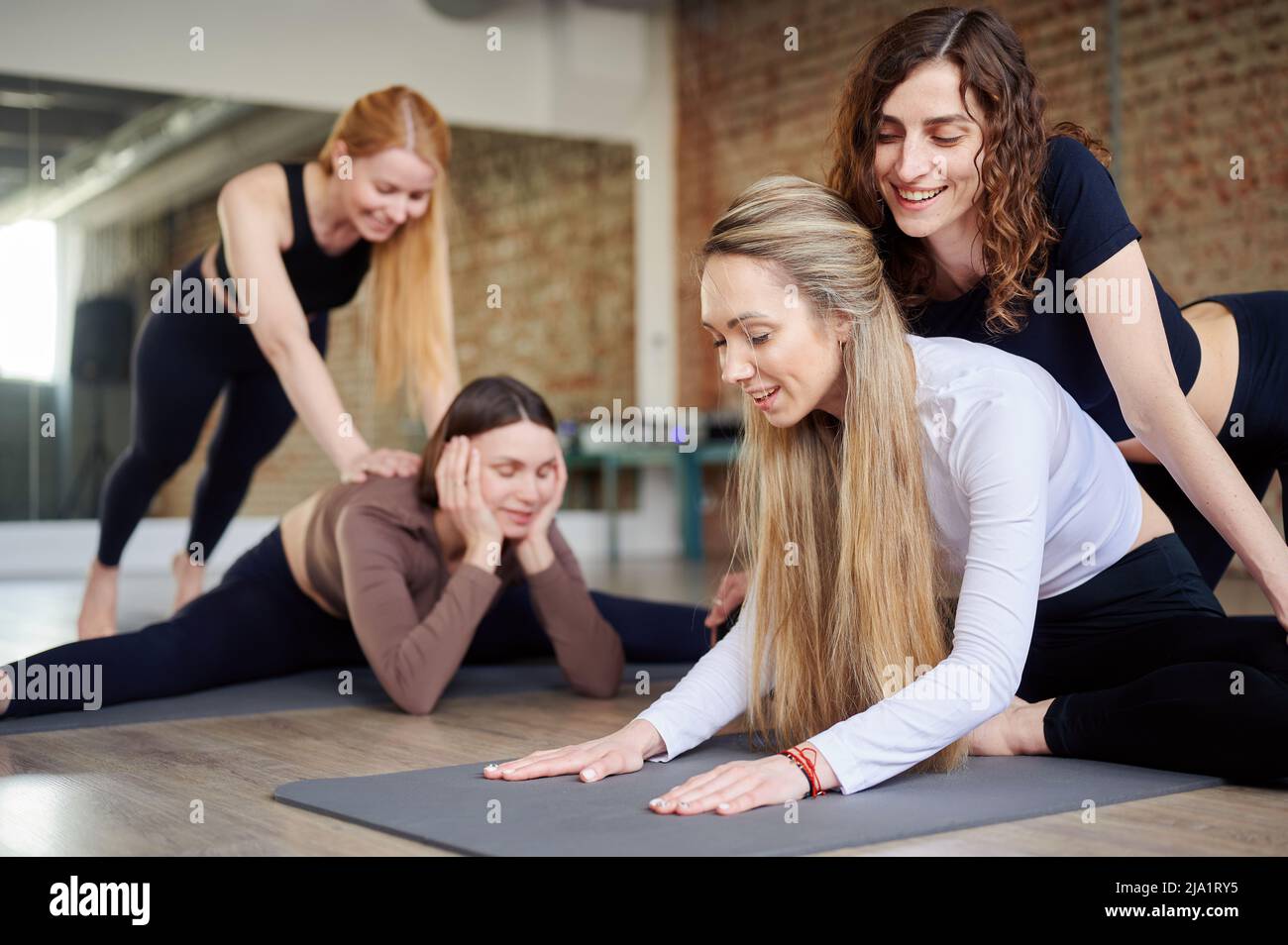 Yoga-Kurs im Fitnessstudio. Mädchen Stretching-Kurs mit Lehrer drinnen auf Yoga-Matte. Fitness, Sport, Training, Gym und Lifestyle Konzept Stockfoto