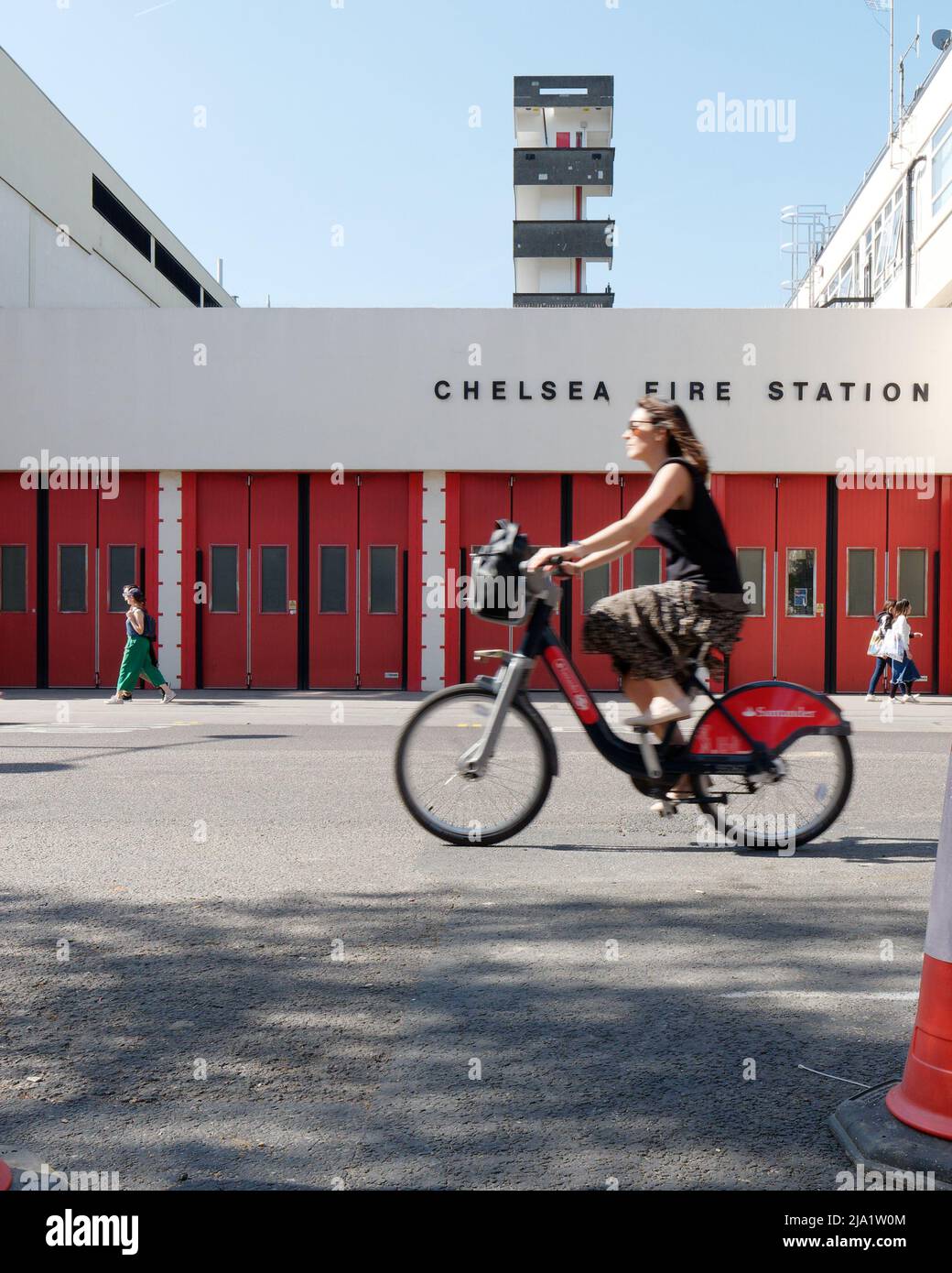 London, Greater London, England, Mai 14 2022: Lady auf einem Mietfahrrad von Santander, auch bekannt als Borris Bike, fährt an der Chelsea Fire Station an der Kings Road vorbei. Stockfoto