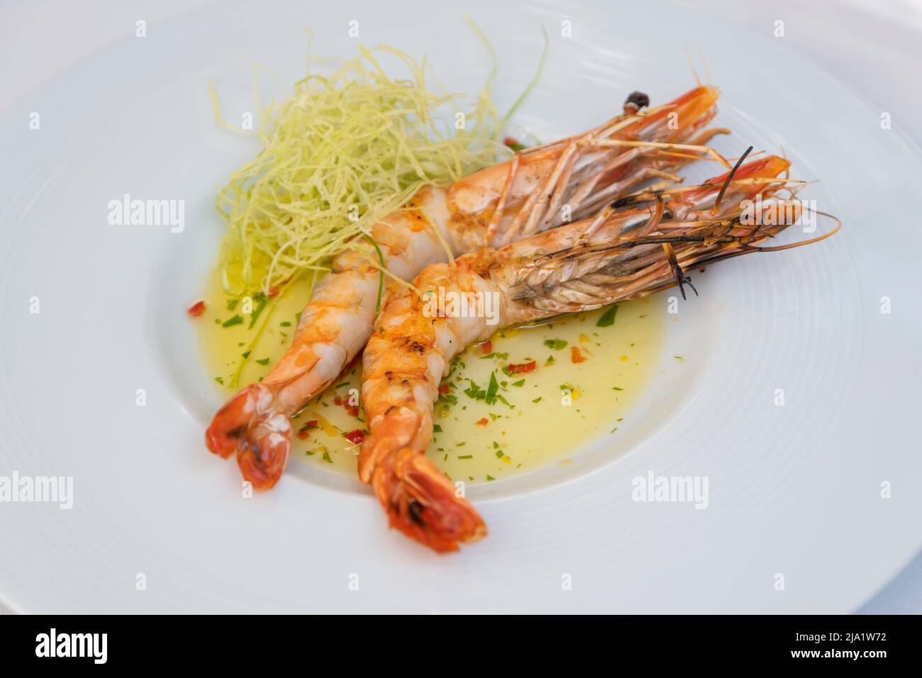 Platte mit gegrillten Garnelen mit Sauce und Gemüseseiten. Präsentation von luxuriösen Restaurantplatten Stockfoto