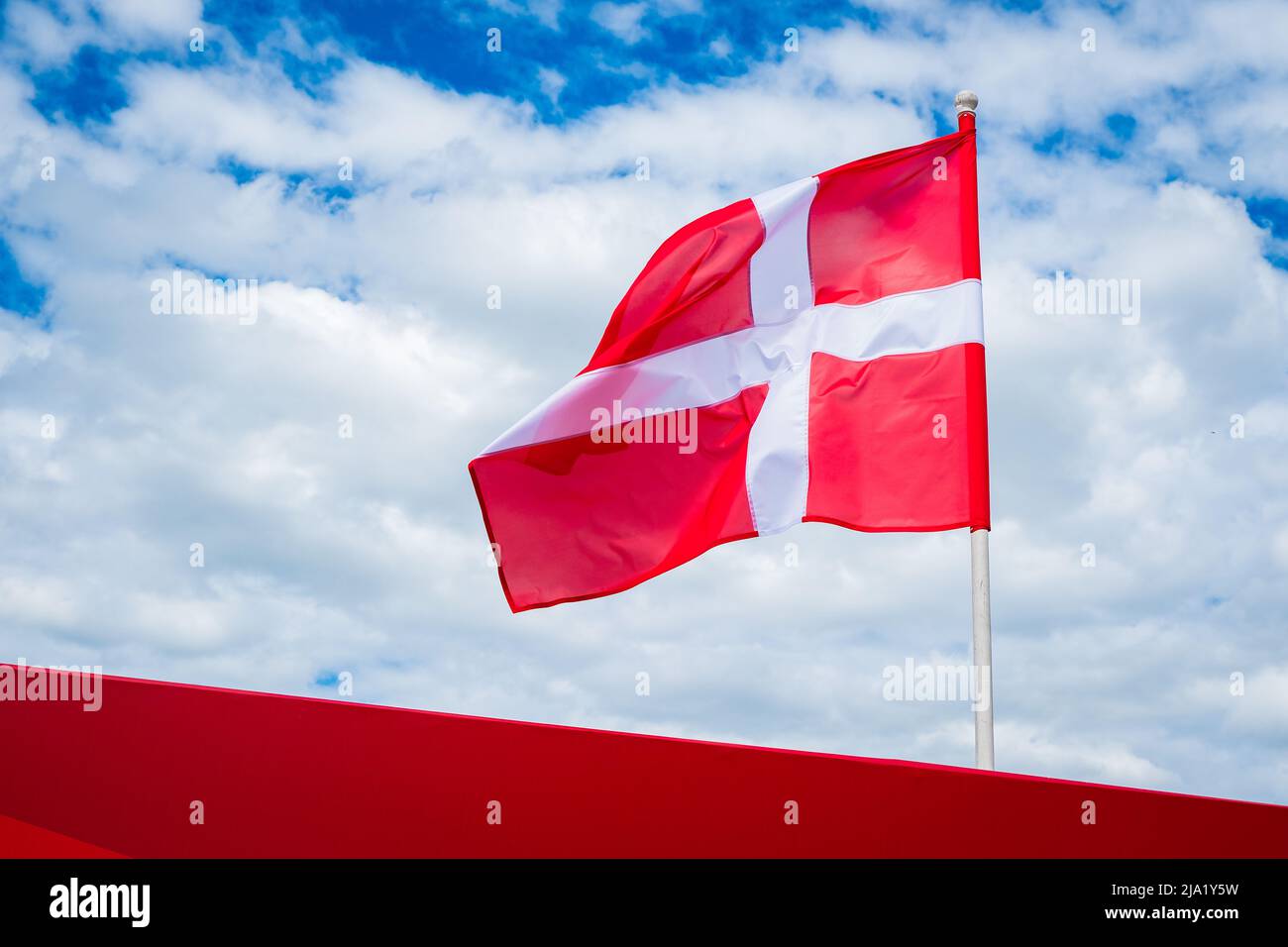 Flagge Dänemarks auf weiß bewölktem Himmel Hintergrund. Dänische Flagge winkt im Wind. Stockfoto