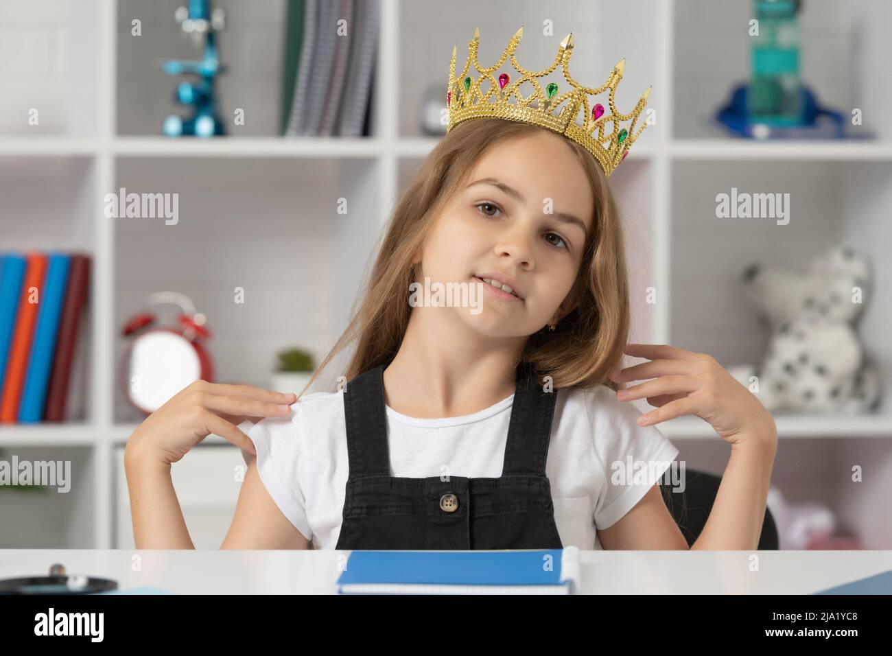 Arrogantes Kind in Königskrone im Klassenzimmer Stockfoto