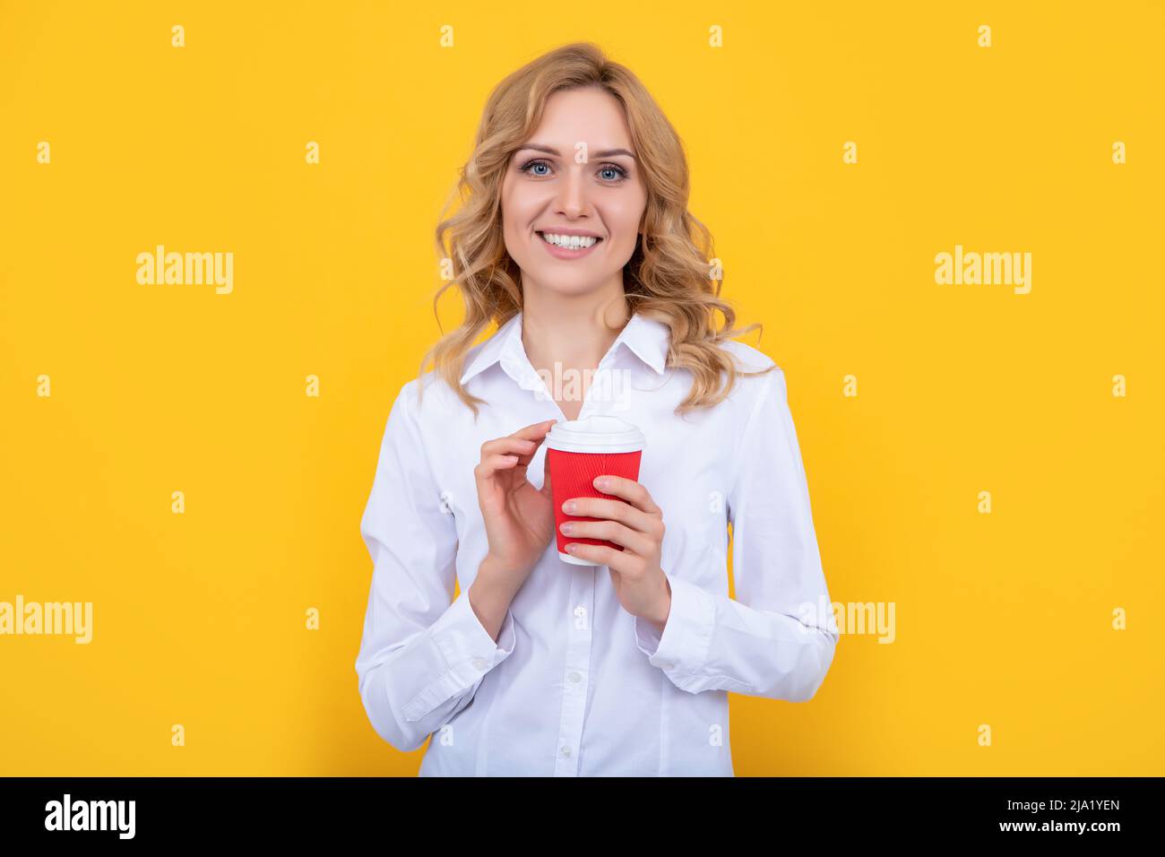 Positive blonde Frau mit Kaffeetasse auf gelbem Hintergrund Stockfoto