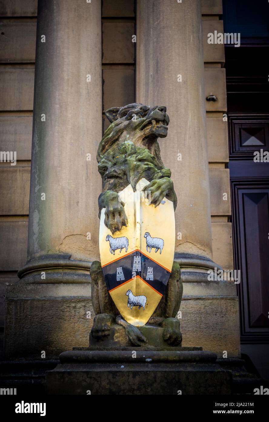Steinlöwenstatue mit einem Schild, eines von einem Paar am Eingang zum Rathaus von Huddersfield. Huddersfield. West Yorkshire. Stockfoto