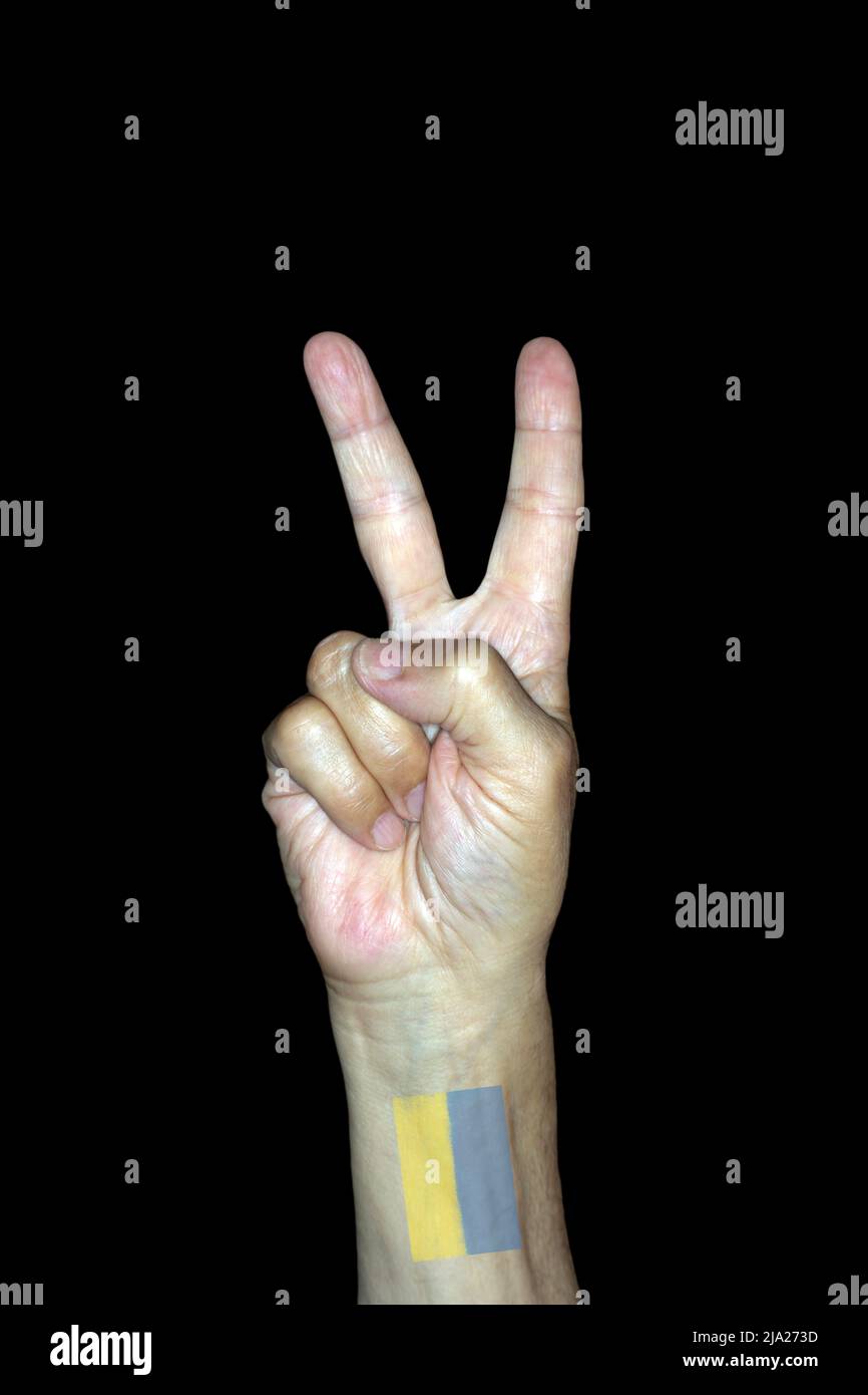 Symbolisches Bild für Sieg und Frieden, männliche Hand mit einem Tattoo der ukrainischen Flagge, Studiofotografie mit schwarzem Hintergrund Stockfoto