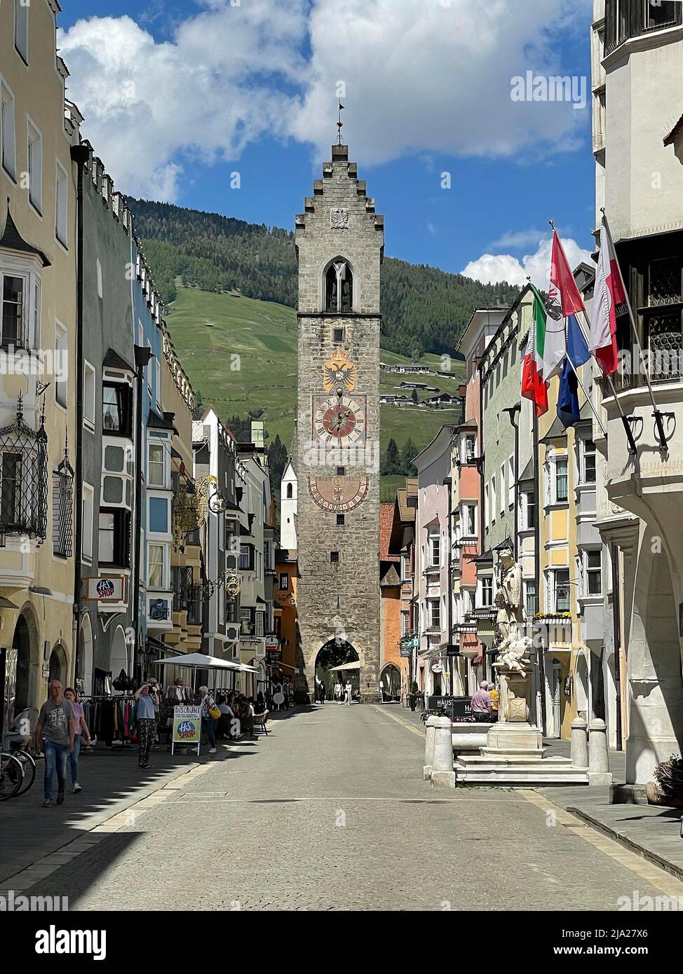 Blick auf den Zwölften Turm in der historischen Neustadt Sterzing, im Vordergrund St.-Johannes-Nepomuk-Brunnen, darüber die italienische Nationalflagge, Flagge Stockfoto