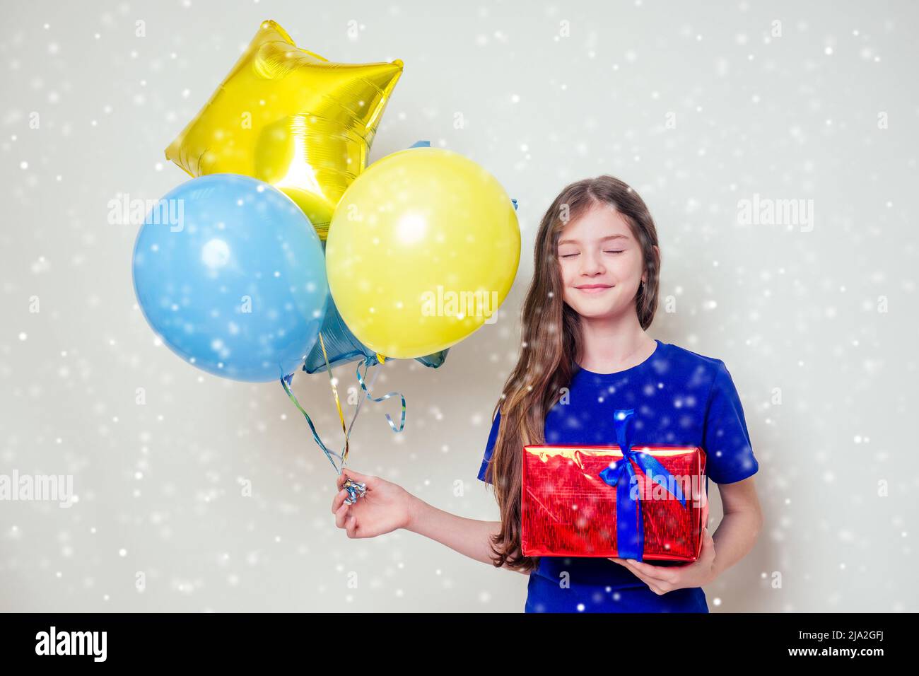 Nettes kleines Mädchen hält Helium blau, gelb und Gold Ballons und eine Box mit einem Geschenk Happy Birthday auf weißem Hintergrund im Studio .christmas und neu Stockfoto