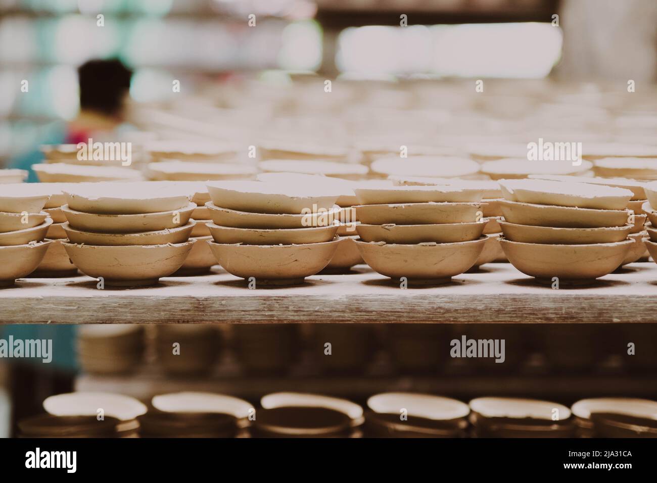 Viele kleine runde Teller aus Keramik-Ton. Keramikbecher im Rack für die Reinigung mit Schleifpapier vorbereiten, bevor das Muster auf das Tonprodukt auftragen. H Stockfoto