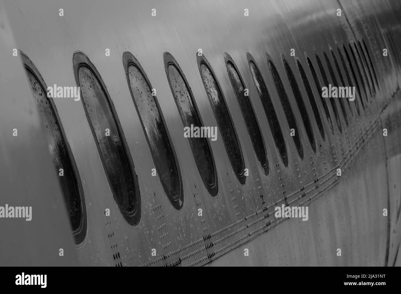 Blick auf den Rumpf des Flugzeugs und viele vom Regen durchnässte Fenster. Stockfoto
