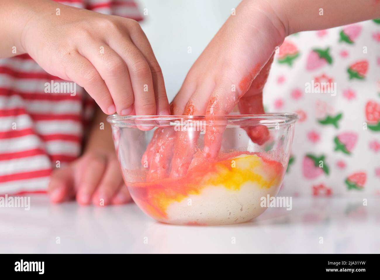 Kinder geben dem Salz in einer Glasschüssel Lebensmittelfarbe hinzu und mischen es mit den Händen. Bunte Salzkunst. DIY Spiel und Lernen Aktivitäten für Kinder. Stockfoto