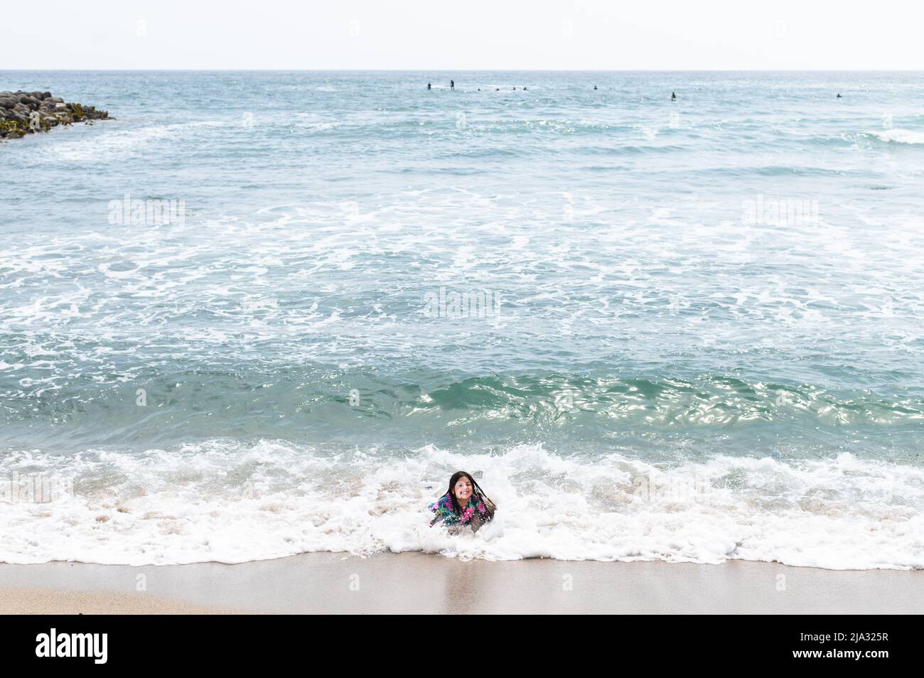 Glückliches Mädchen, das am Ufer des Strandes von San Bartolo südlich von Lima - Peru sitzt. Sommerurlaub Stockfoto