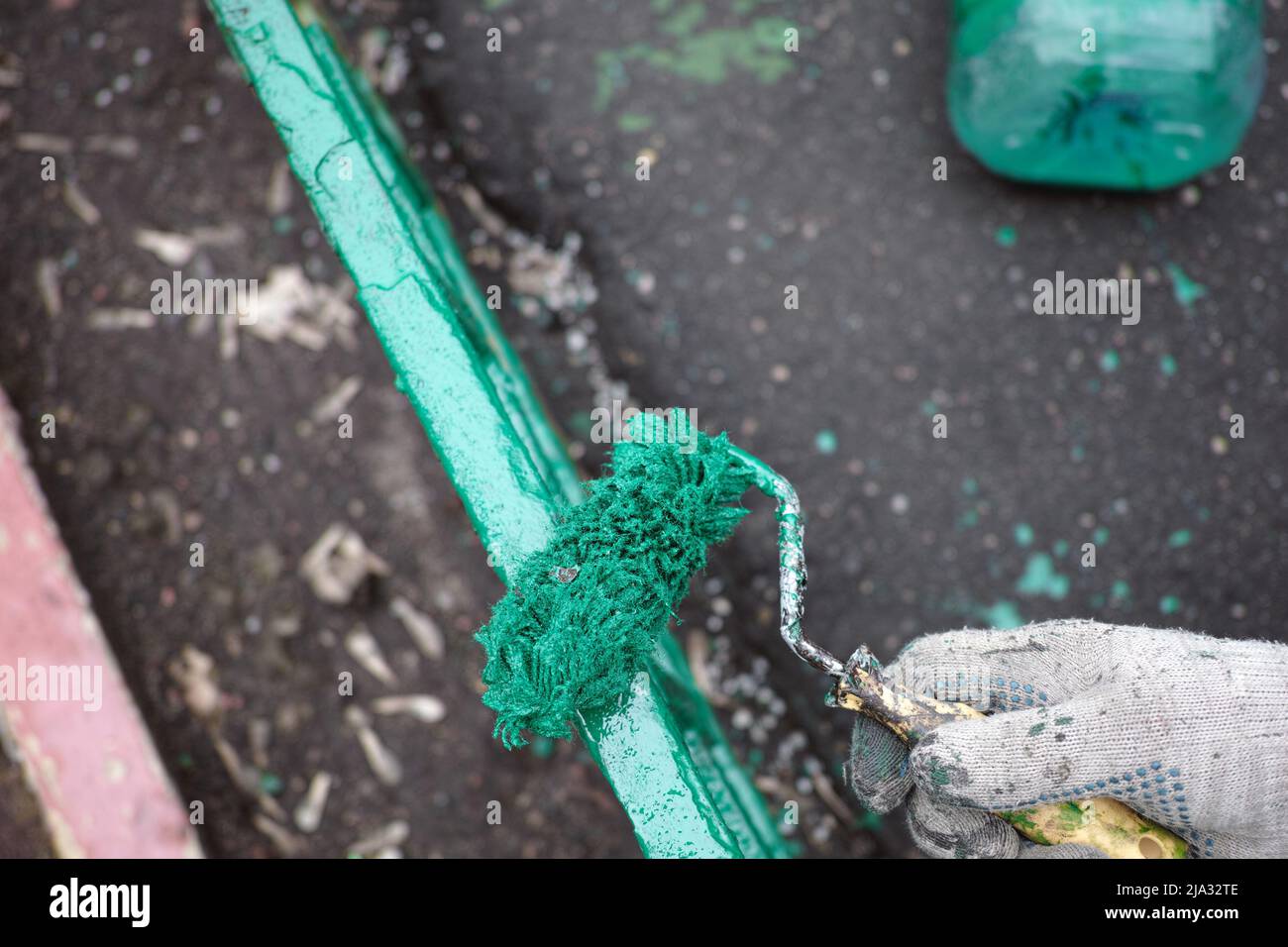 Frisch gedrehten grünen Zaun und eine Walze zum Malen in einem Handschuh tragen Stockfoto