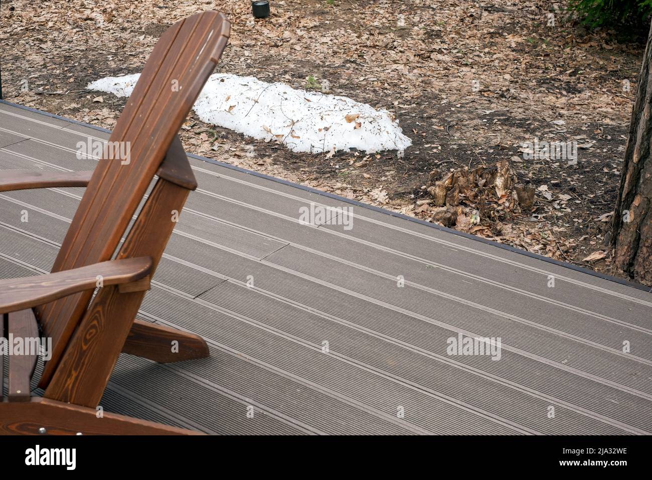 Letzter Schnee auf dem Boden neben einer Terrasse mit Holzboden, Frühlingsaufnahme im Freien Stockfoto