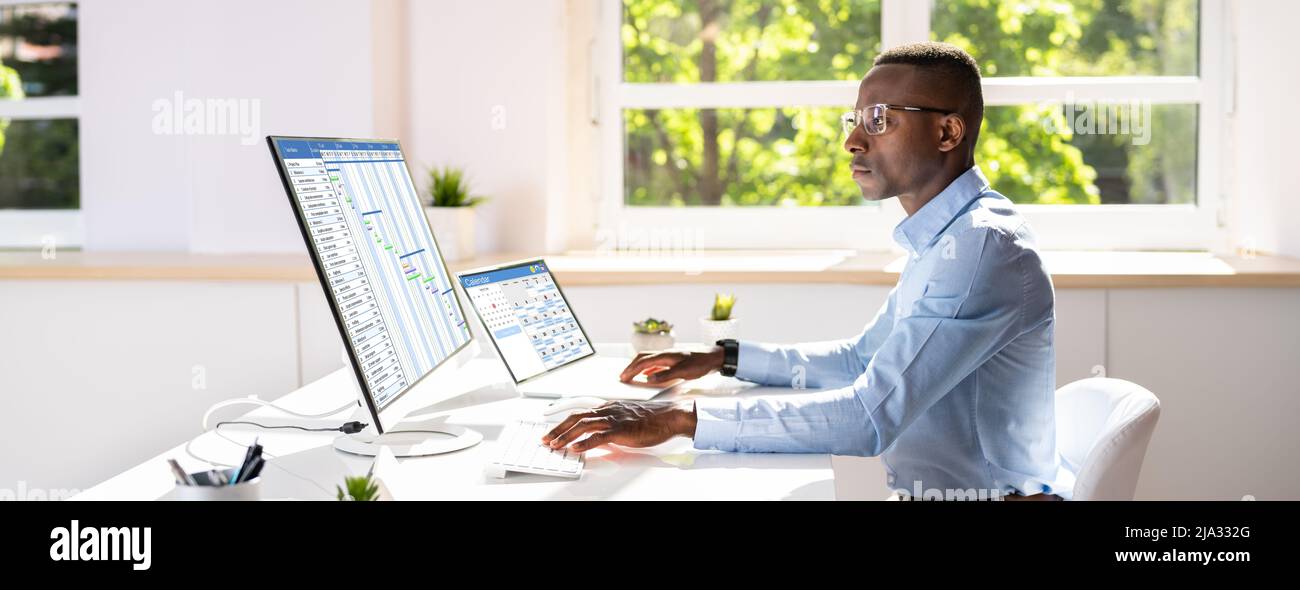 Seitenansicht eines Junge Unternehmer mit Blick auf das Gantt-diagramm auf Computer im Büro Stockfoto
