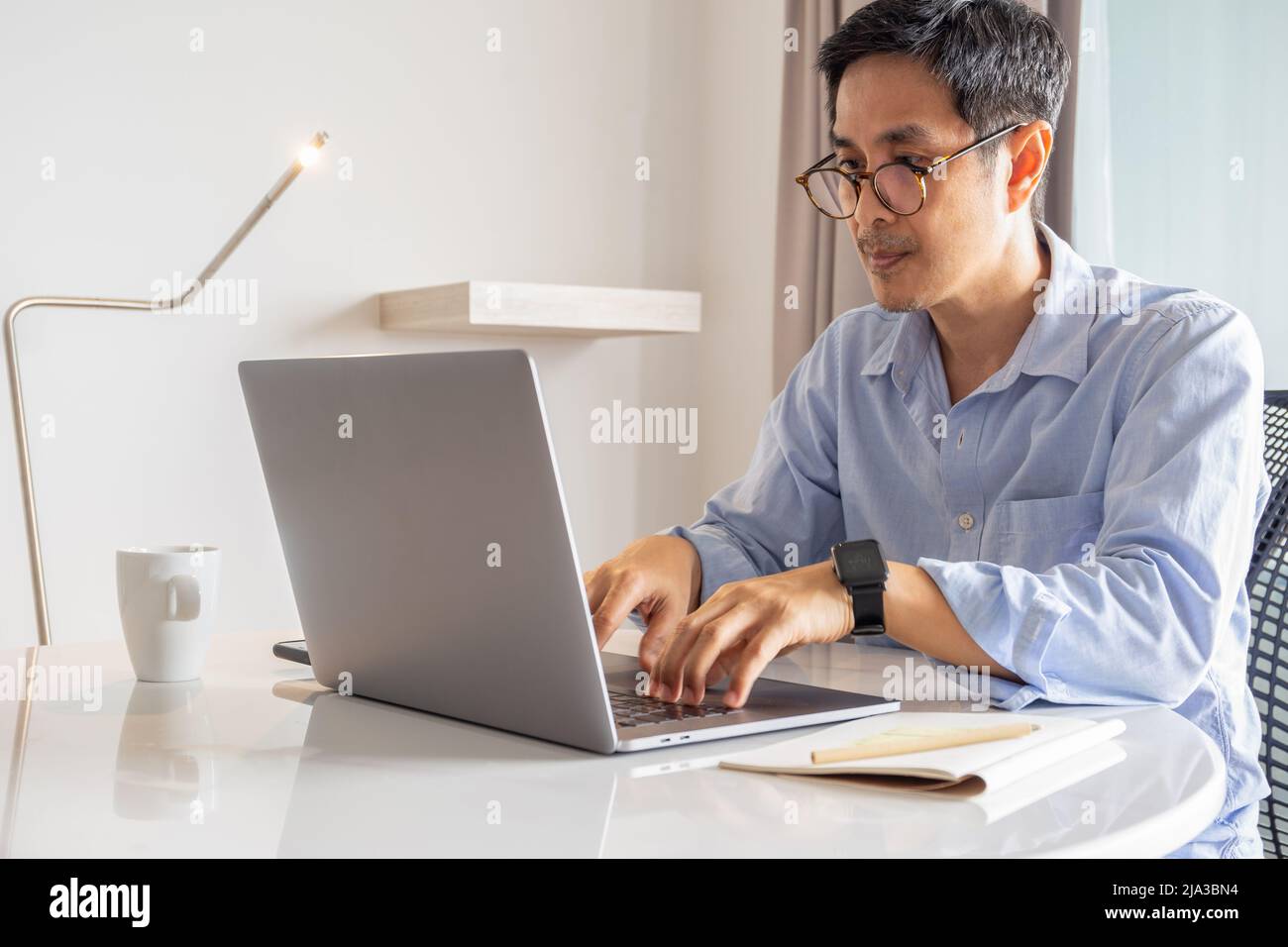 Geschäftsmann, der zu Hause mit dem Laptop auf der Tastatur arbeitet. Stockfoto