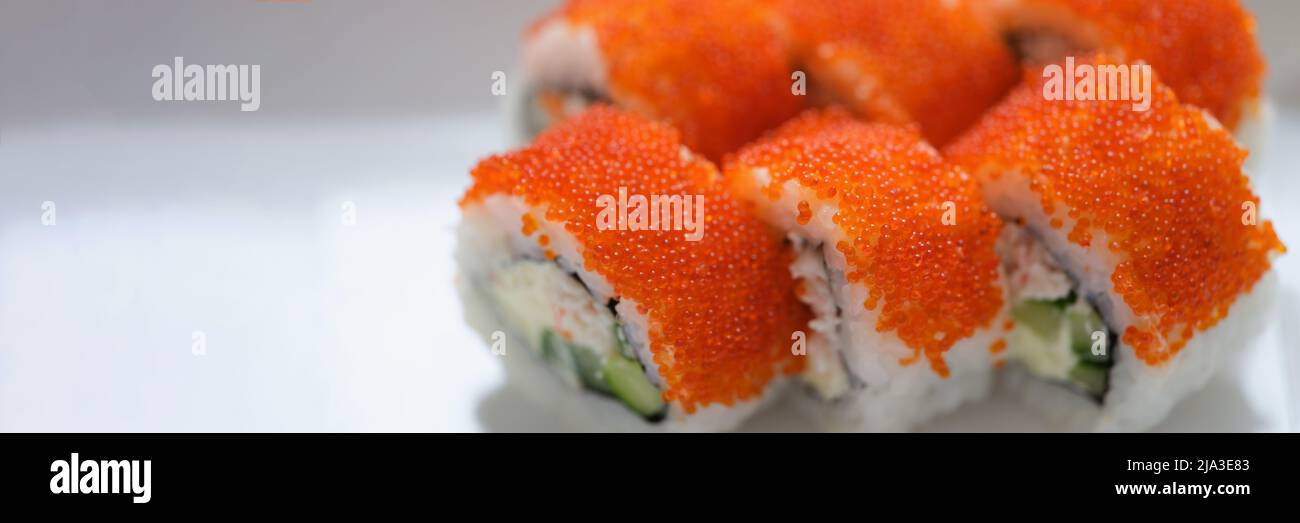 Sushi mit orange fliegendem Fischkaviar auf einem weißen Teller Stockfoto