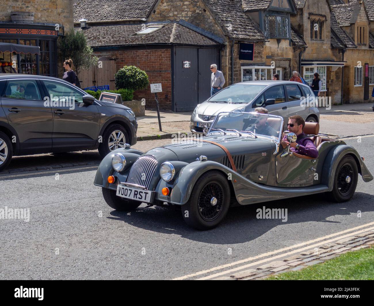 Open-Top-Sportwagen von Morgan, der an einem sonnigen Tag durch die Cotswold-Stadt Broadway fährt; Worcestershire, Großbritannien Stockfoto