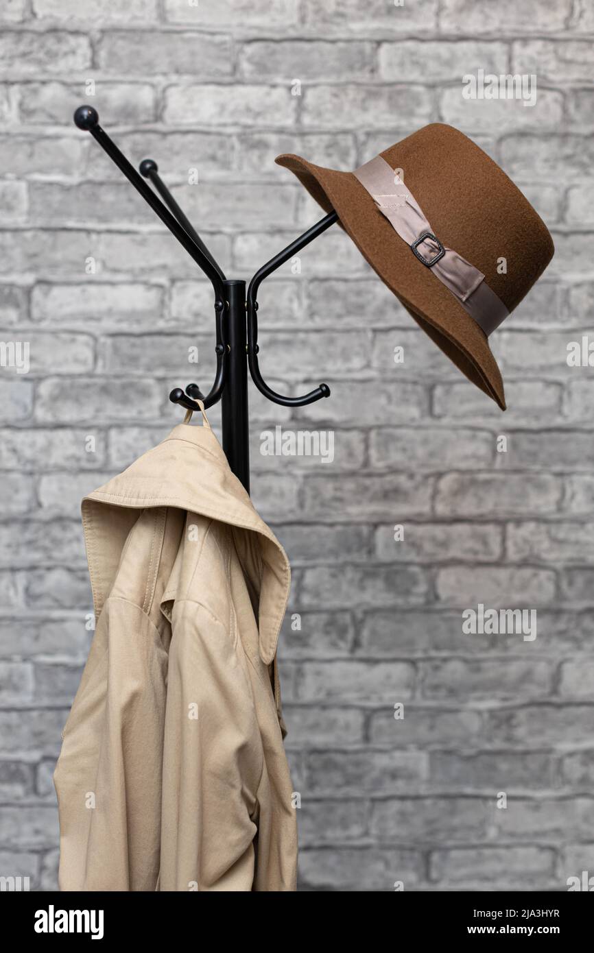 Ein Hut und ein Regenmantel hängen an einem Metallbodenbügel. Hochwertige Fotos Stockfoto