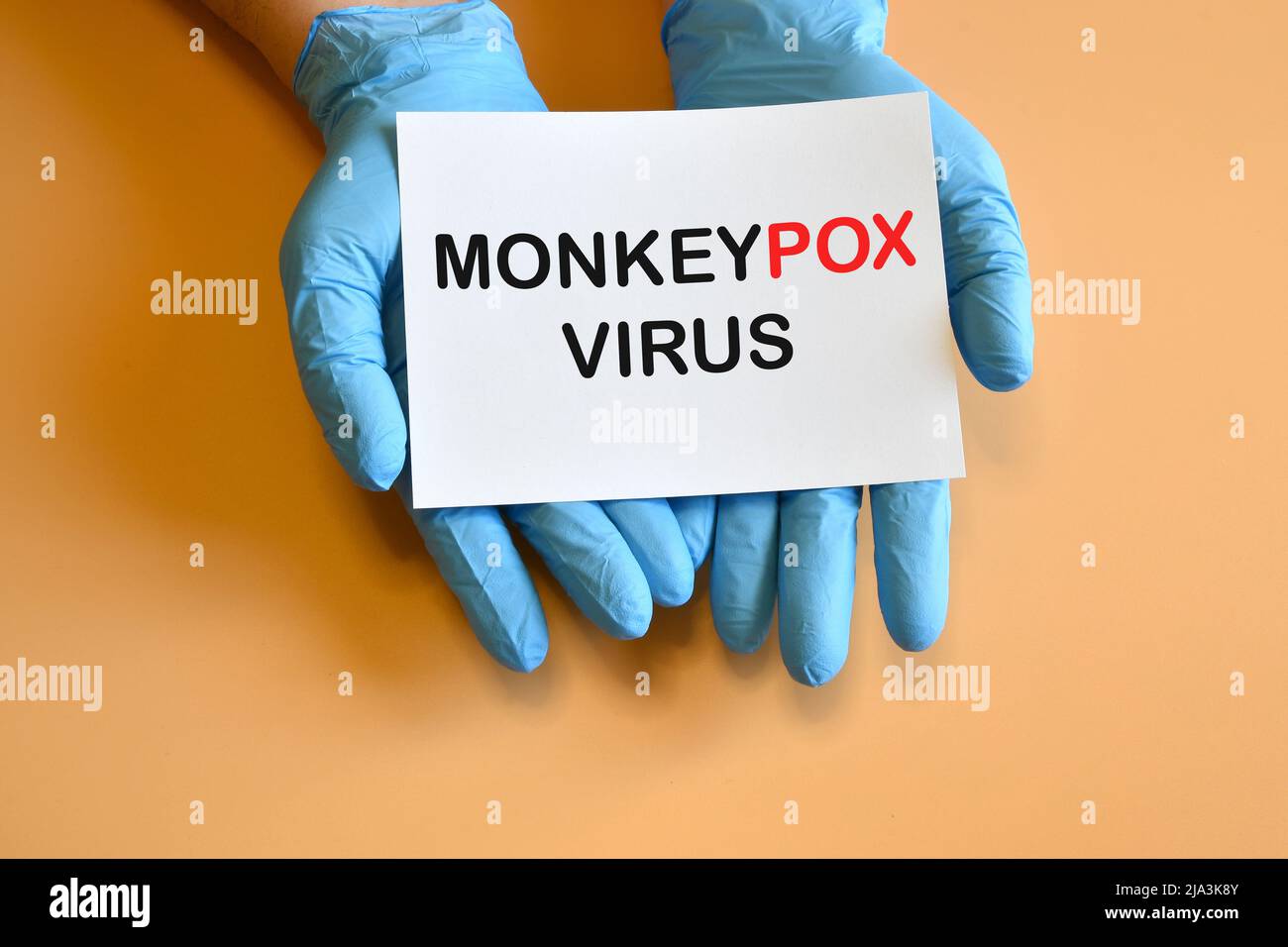 Monkeypox-Virus. Die Hände des Arztes in blauen Handschuhen halten ein weißes Papier mit der Aufschrift „Monkeypox Virus“. Stockfoto
