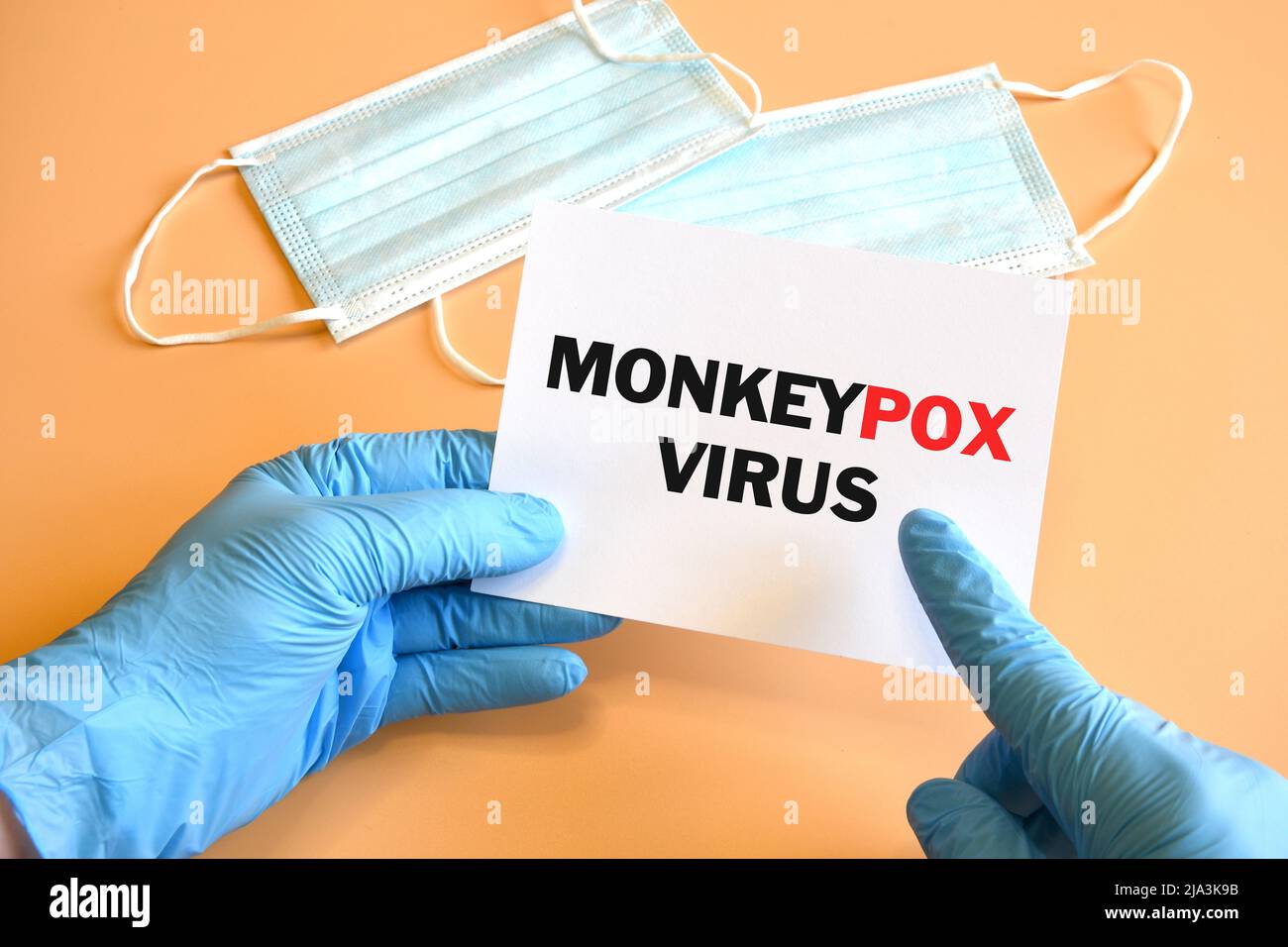 Doktor Hand in blauem Handschuh zeigen monkeypox Virus Wörter auf weißem Papier an. Monkeypox auf weißem Papier. Medizinisches und monkeypox-Virus-Pandemiekonzept. Stockfoto