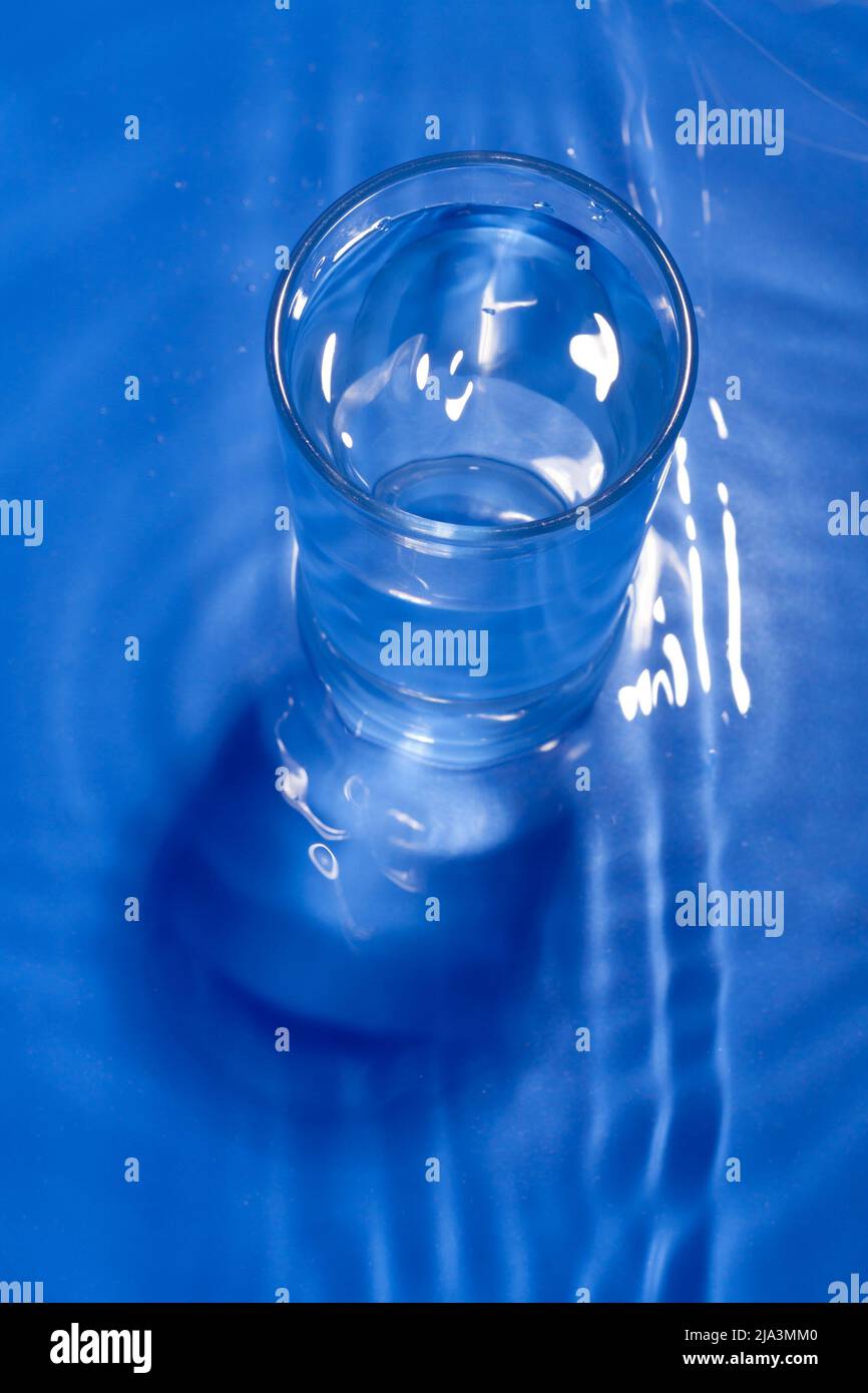 Dunkelblaues monochromes Bild eines Glases Wasser. Stockfoto