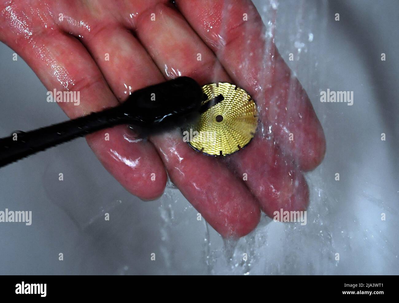 (220527) -- XINMI, 27. Mai 2022 (Xinhua) -- Cheng Yucai wäscht ein Zifferblatt, nachdem er es am 24. Mai 2022 in seiner Werkstatt in Xinmi, der zentralchinesischen Provinz Henan, erwärmt hatte. Guilloche ist eine dekorative Technik, bei der ein präzises, kompliziertes und sich wiederholendes Muster mechanisch durch Drehen des Motors in ein Material eingraviert wird. Die Technik verwendet eine Maschine, die von der Zartheit der Hand des Handwerkers gesteuert wird. Als ein wichtiger Prozess bei der Herstellung überlegener Uhren und Schmuck, wird die Kunst heute von selten wenigen Menschen gemeistert. Cheng Yucai, geboren 1978, lernte Guilloche 2013 kennen, als er einen Zigarettenkoffer dec sah Stockfoto