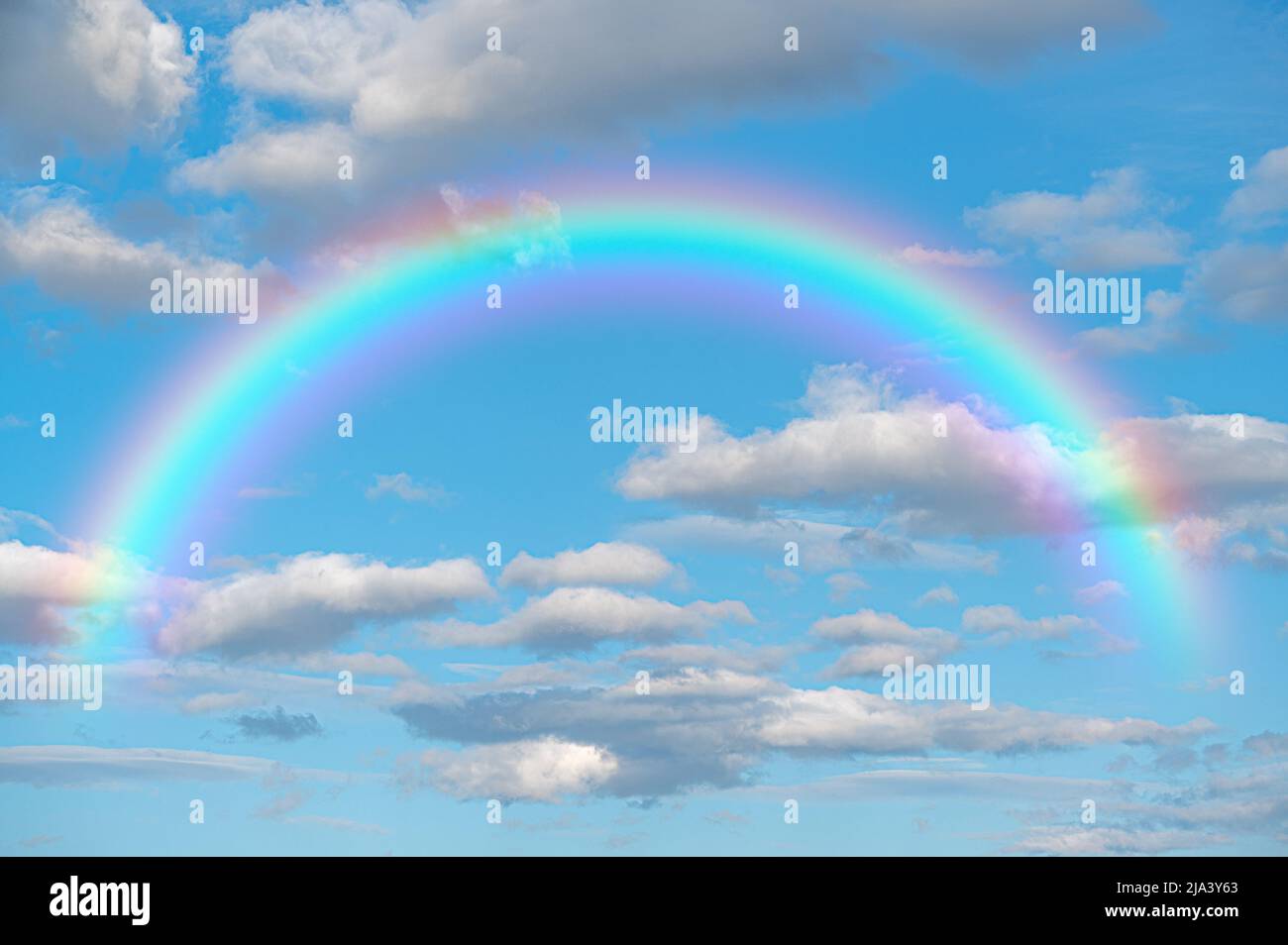 Regenbogenhimmel. Atemberaubender blauer Himmel Regenbogen große, flauschige Wolken mit riesigem Regenbogen gegen den wunderschönen blauen Himmel im Sommer mit Platz für Nachrichten Stockfoto