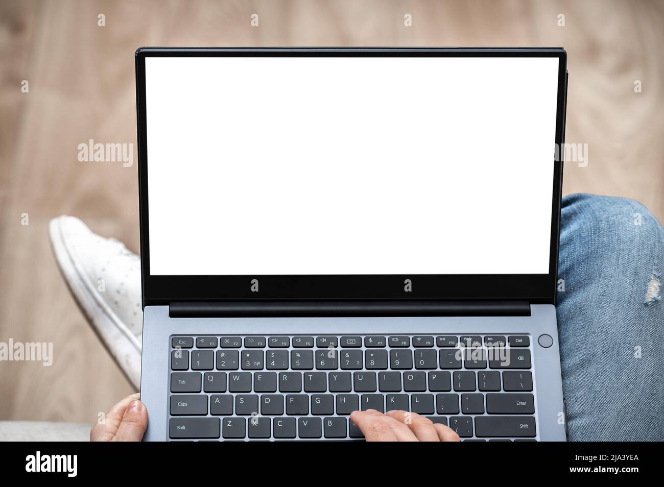 Draufsicht Mockup-Bild einer Frau, die auf einem Laptop-Computer mit leerem Bildschirm arbeitet und tippt, während sie zu Hause auf dem Sofa sitzt. Hand mit Laptop mit leerem w Stockfoto