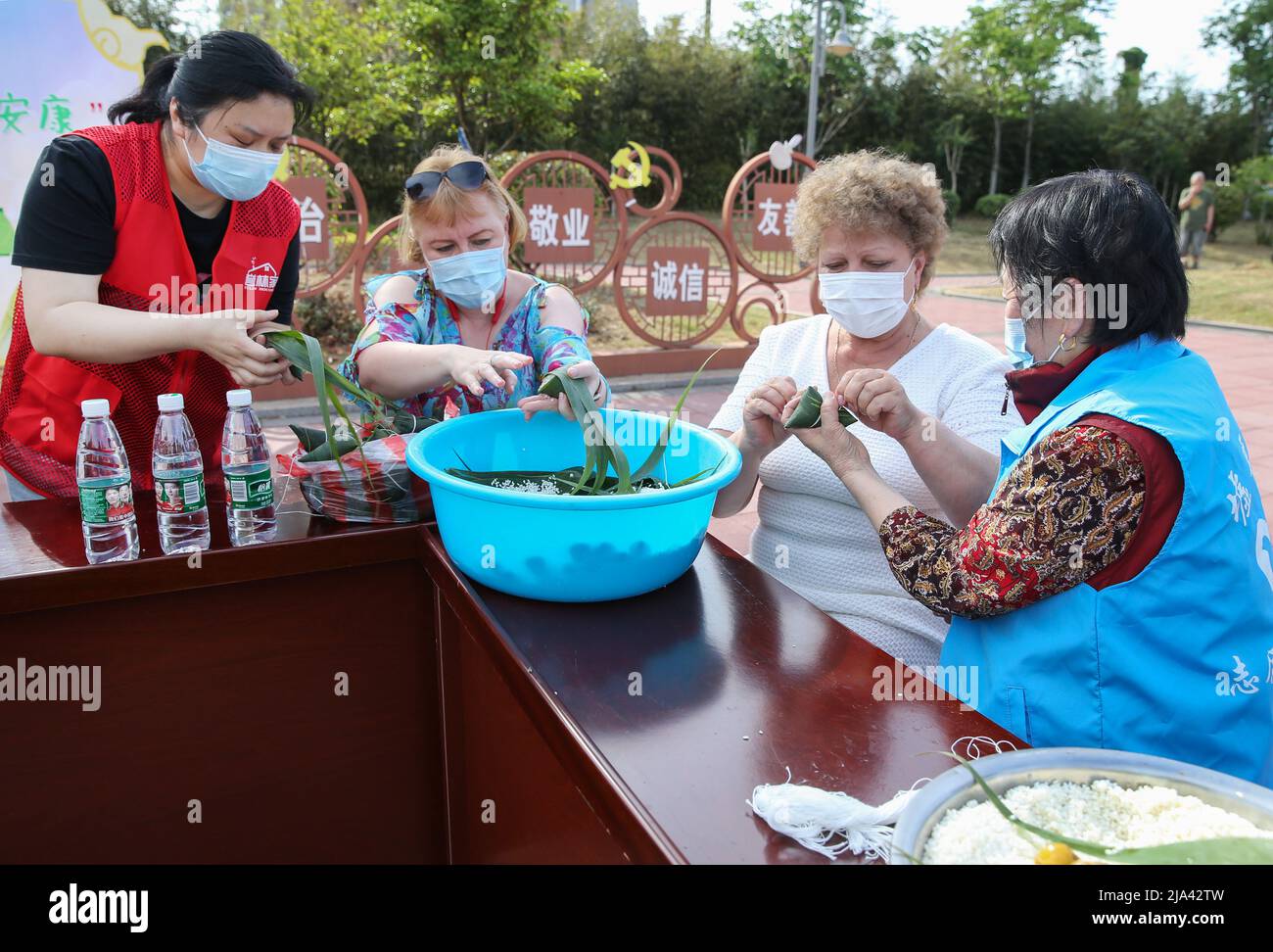 LIANYUNGANG, CHINA - 27. MAI 2022 - Freiwillige der Gemeinschaft führen ausländische Freunde an, um Zongzi in lianyungang, der ostchinesischen Provinz Jiangsu, zu machen Stockfoto