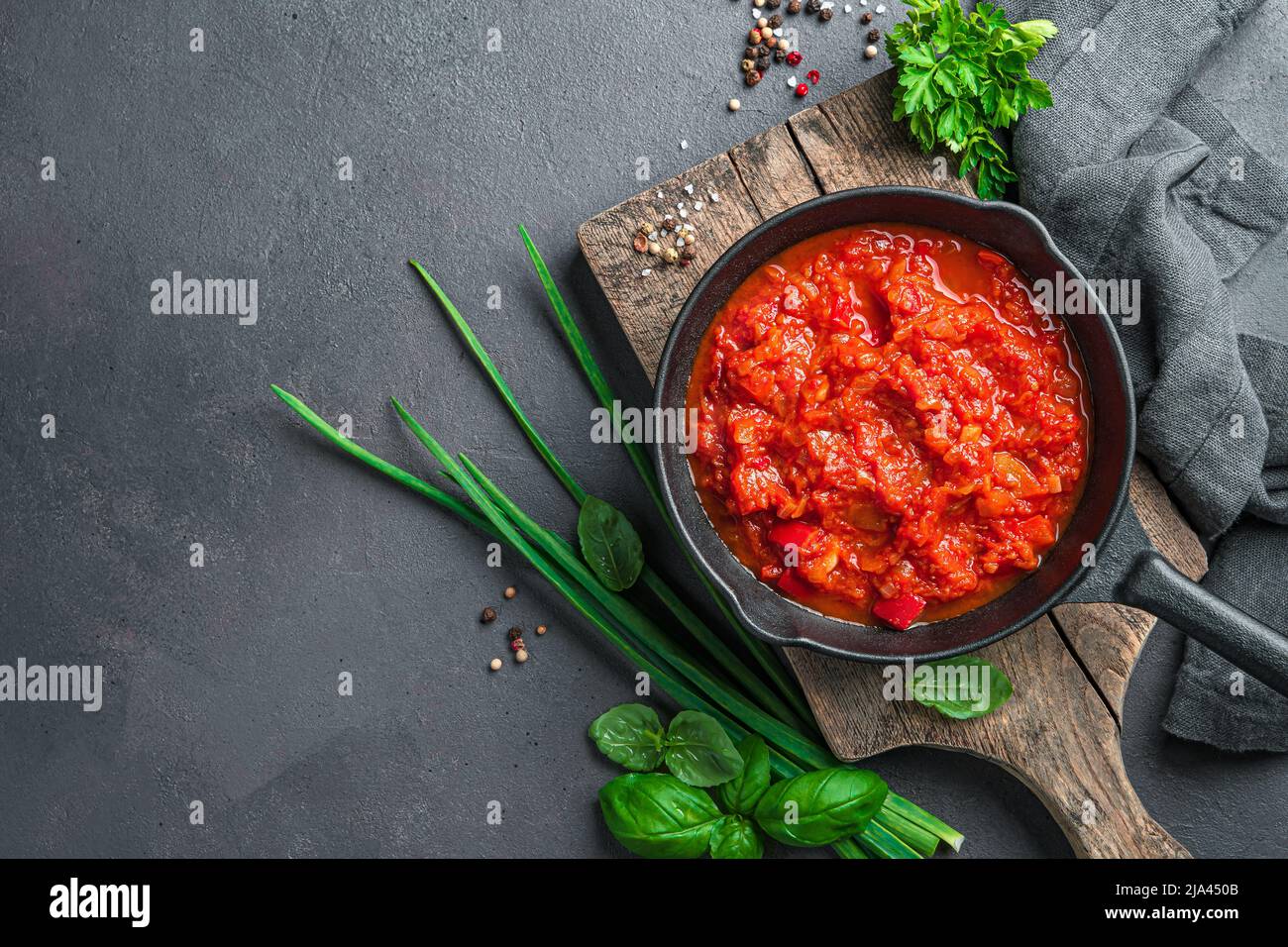 Hausgemachte Tomatensauce und frische Kräuter auf dunklem Hintergrund. Stockfoto