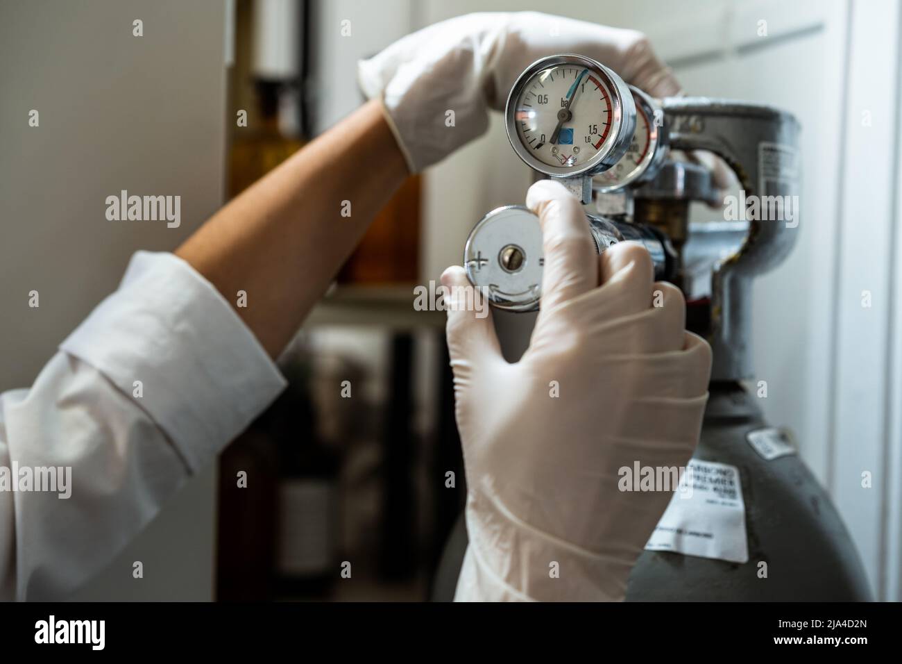 Nahaufnahme der Hände eines Technikers in Handschuhen, die ein Barometer einer Stickstoffflasche oder Druckluft einstellen Stockfoto