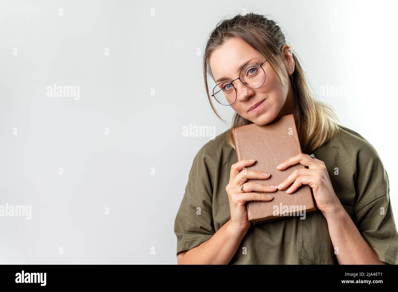 Junge glückliche Studentin, die Bücher vor ihrem Gesicht auf weißem Hintergrund hält Stockfoto