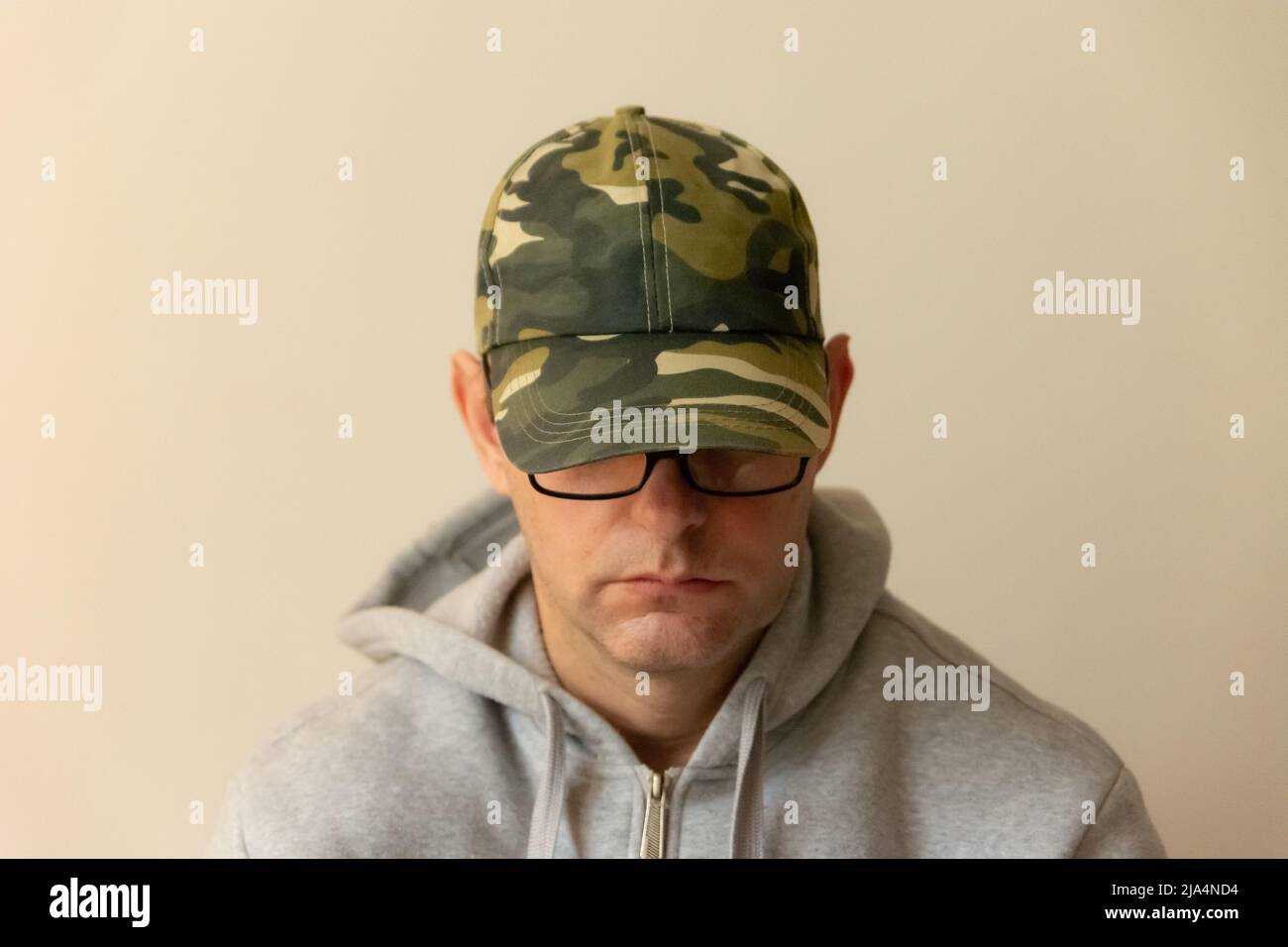 Trauriger Einzelmensch mit Brille und gesenktem Kopf Stockfoto