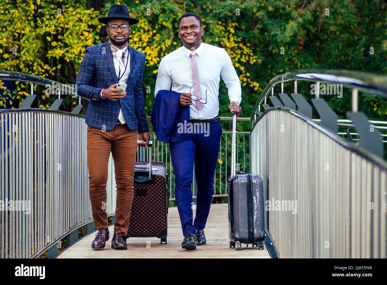 Zwei afroamerikanische Geschäftspartner begeben sich zu einer internationalen Konferenz für ein Geschäftstreffen in Richtung Flughafen Stockfoto