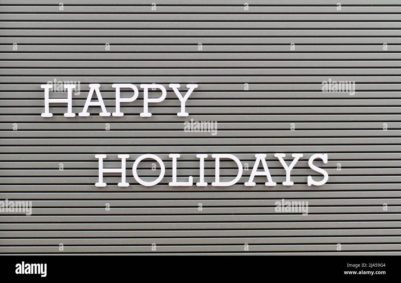 Frohe Feiertage mit Plastikbuchstaben auf grauer geschichteter Oberfläche geschrieben Stockfoto