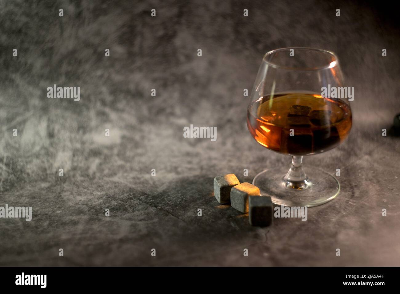 Transparenter Whiskey auf dunklem Hintergrund. Whiskey-Steine im Glas Stockfoto