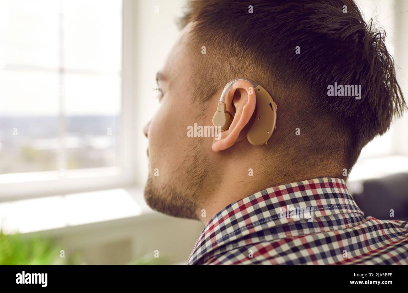 Nahaufnahme eines jungen Mannes, der sein Gehör mit einem Hörgerät am Ohr verloren hat Stockfoto
