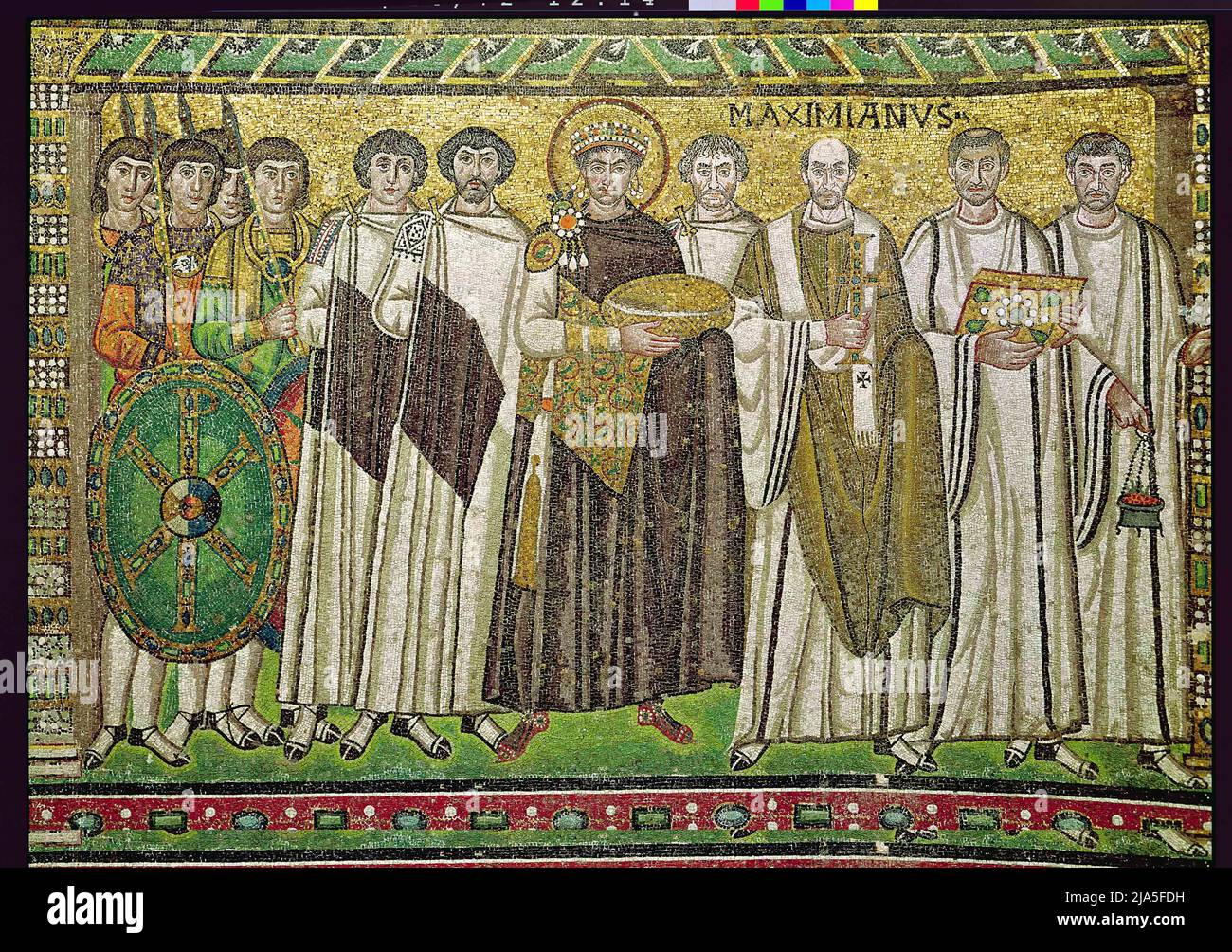 Justinian I (483-565) ist dargestellt, der möglicherweise das Brot der Eucharistie oder eine Patene oder einen symbolischen Korb für die Würdigung trägt; rechts von ihm möglicherweise Belisarius und links möglicherweise der Bankier Julianus Argentarius, der für den Bau der Kirche bezahlt hat; ebenfalls zu sehen ist Maximian, Erzbischof von Ravenna von 545-553; Die Gruppe der Soldaten trägt einen Schild mit dem Chi-Rho-Emblem, der auf den Sieg Konstantins bei der Schlacht an der Milvianischen Brücke im Jahr 312 n. Chr. anspielt; Archibishop Maximian; Stockfoto