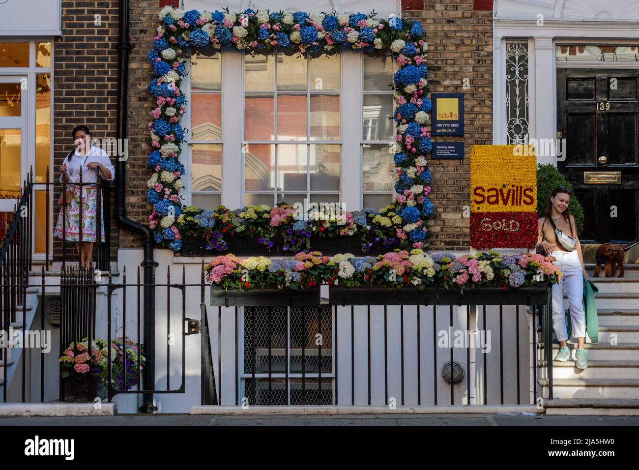 Chelsea, London, Großbritannien, 27.. Mai 2022.Besucher posieren mit Blumeninstallationen auf Chelseas jährlichem, kostenlosen Blumenfestival "Chelsea in Bloom", das vom 23. Bis 28.. Mai 2022 stattfindet.Dieses Jahr steht das Thema "British Icons". Amanda Rose/Alamy Live News Stockfoto