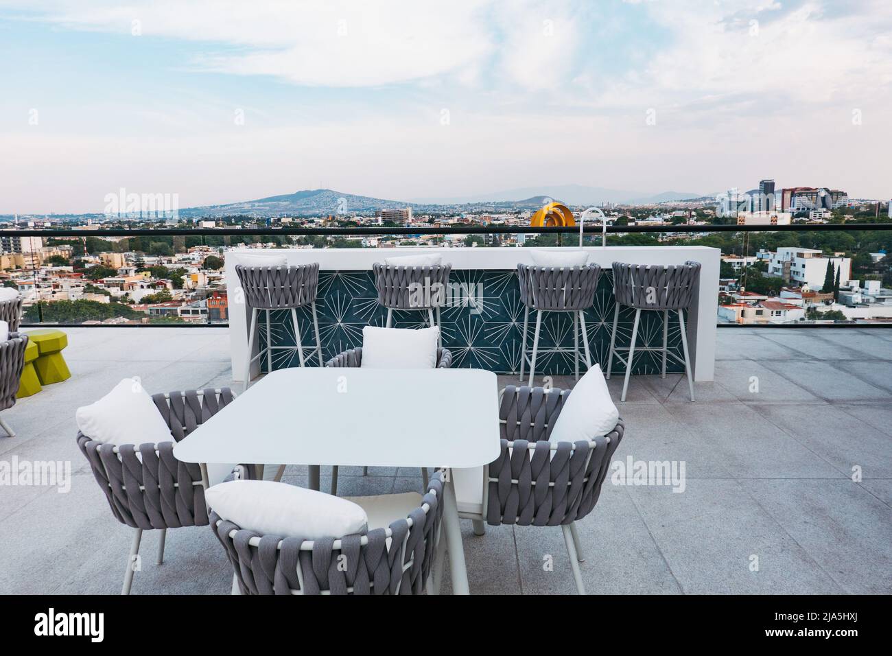 Vom Dach eines neuen Apartmentkomplexes in Jardines del Bosque, Guadalajara, Mexiko, blicken Sitzplätze und ein Tisch auf die Skyline Stockfoto